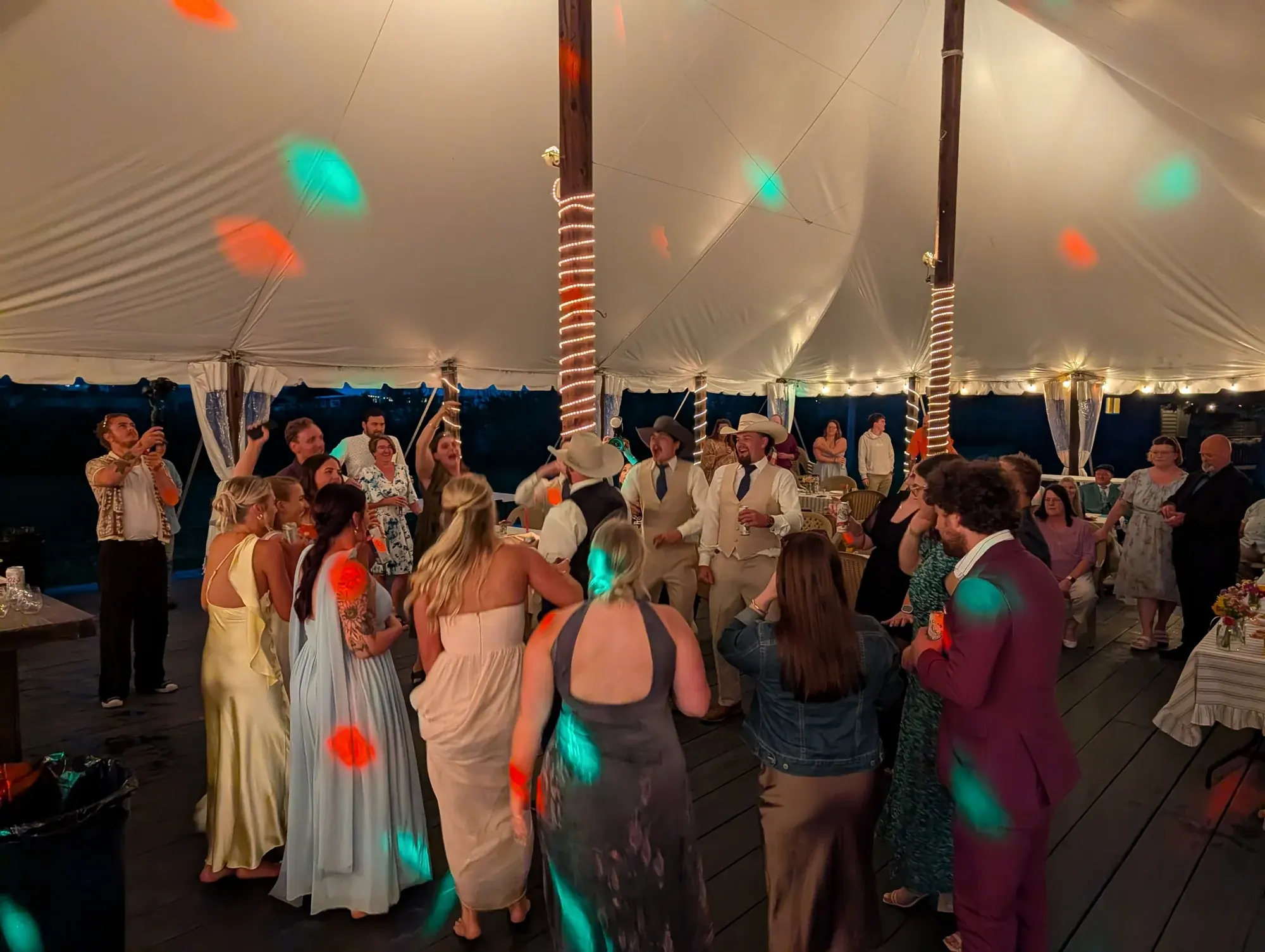 Wedding guests filling the dance floor under a reception tent